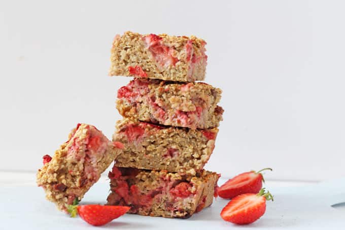 Strawberry Quinoa Breakfast Bars cut into squares and stacked up with slices fresh strawberries in the foreground