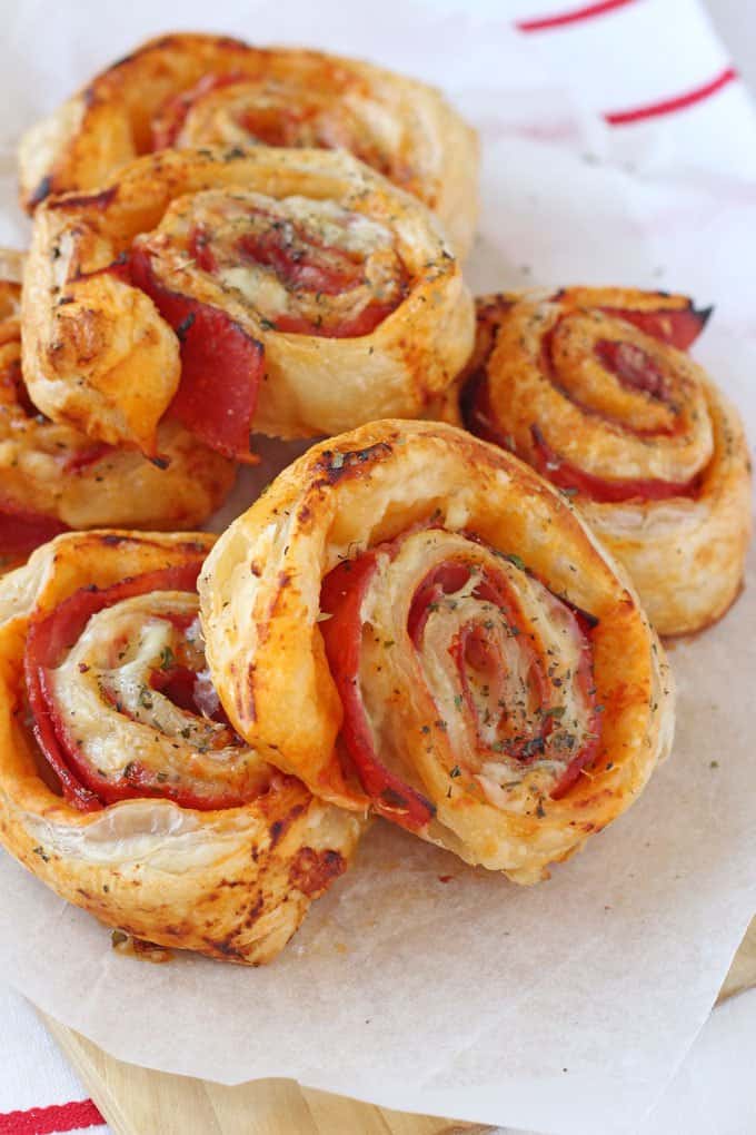 Easy Summer Lunches For Kids - Ham & Cheese Puff Pastry Roll Ups stacked on a wooden chopping board