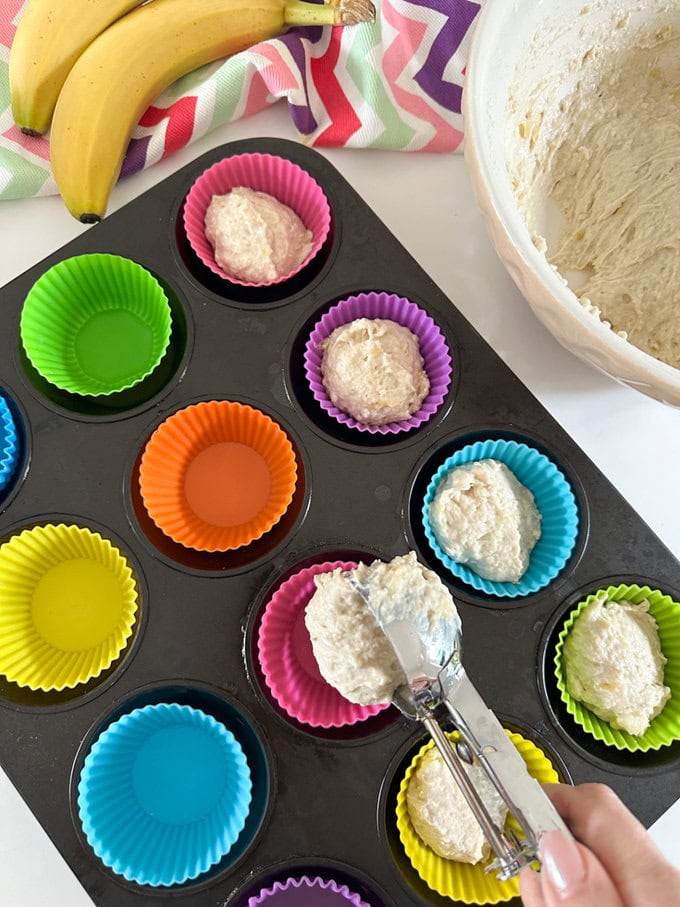 Muffin Mixture being transferred using an ice cream scoop into muffin cases.It makes it much easier than using a spoon.